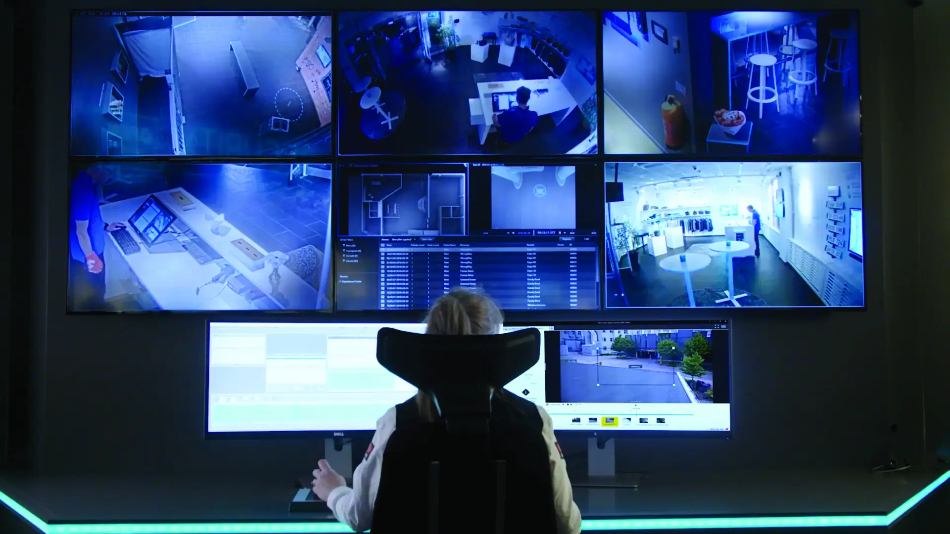 Person watching multiple screens showing surveillance of multiple locations at once.